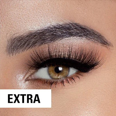 A close-up of a persons eye with dramatic makeup, featuring thick black eyeliner, long voluminous false eyelashes, and a well-groomed eyebrow. The word EXTRA appears in bold letters in the corner.