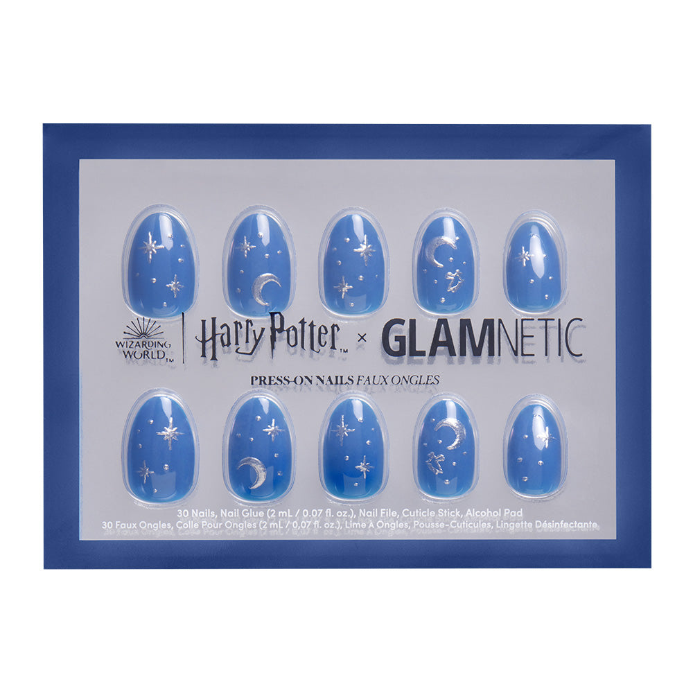 The Luna Lovegood™ nail set by glamnetic includes short oval blue nails with silver Harry Potter-themed and celestial designs, plus foil accents, all arranged in a branded tray.