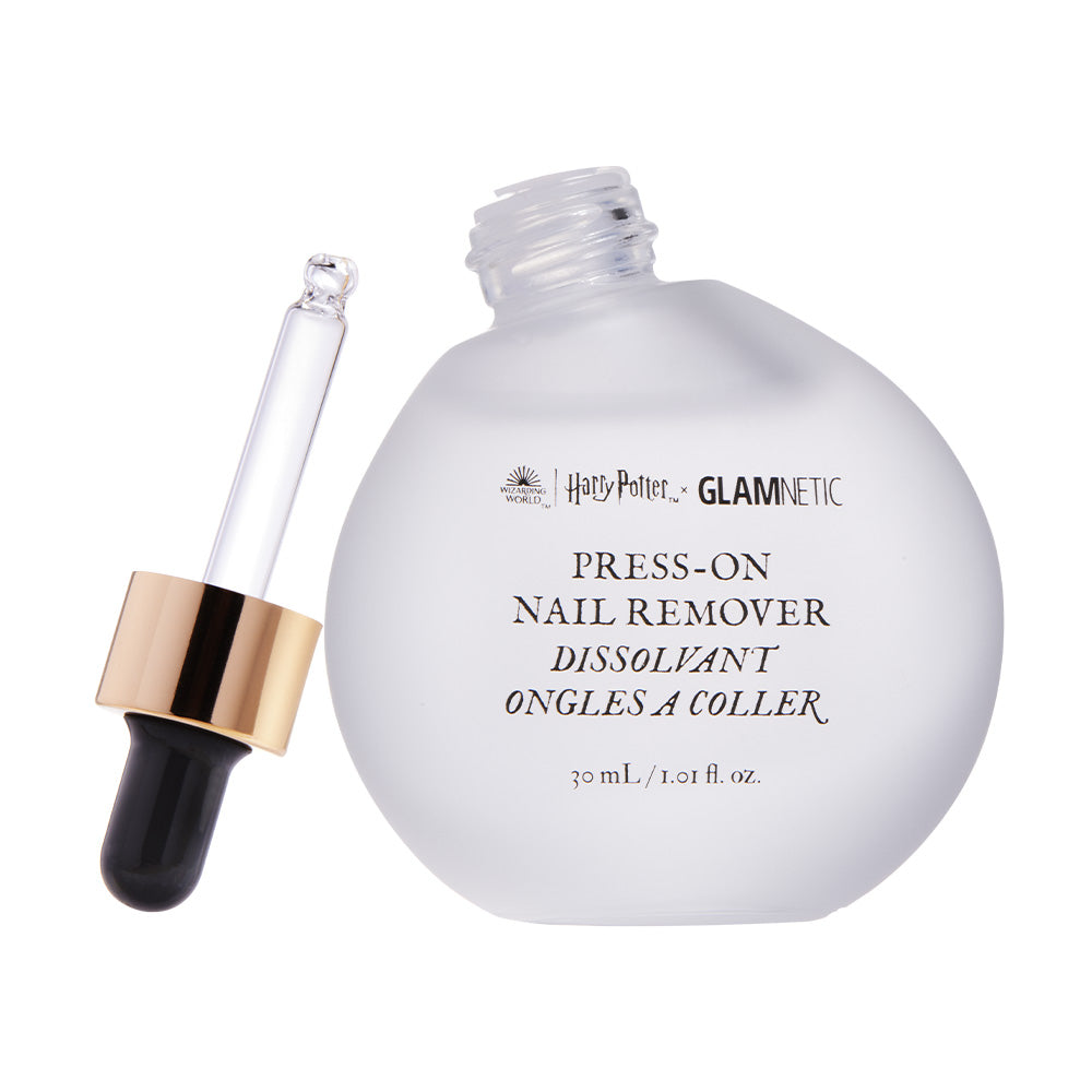 A round frosted bottle labeled Harry Potter™ Press-On Nail Remover by glamnetic, with a gold and black dropper cap, containing 30 mL (1.01 fl oz) of gentle, acetone-free formula, lies beside it. - Product image