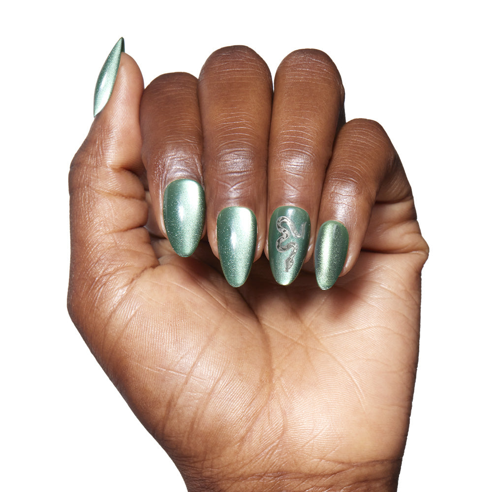A medium-dark hand displays long, almond-shaped emerald green glamnetic Slytherin™ nails with a velvet finish; the ring finger features a black lizard design. Set against a white background, it’s the perfect Slytherin™ look. - Product image