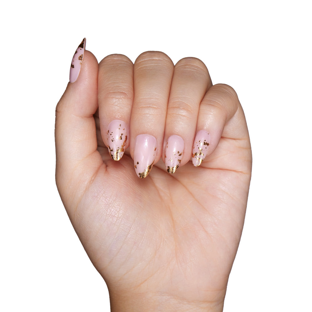 A hand with short almond-shaped nails painted in glamnetics 24K, a light pink shade with gold foil tip accents, is shown against a white background. - Product image