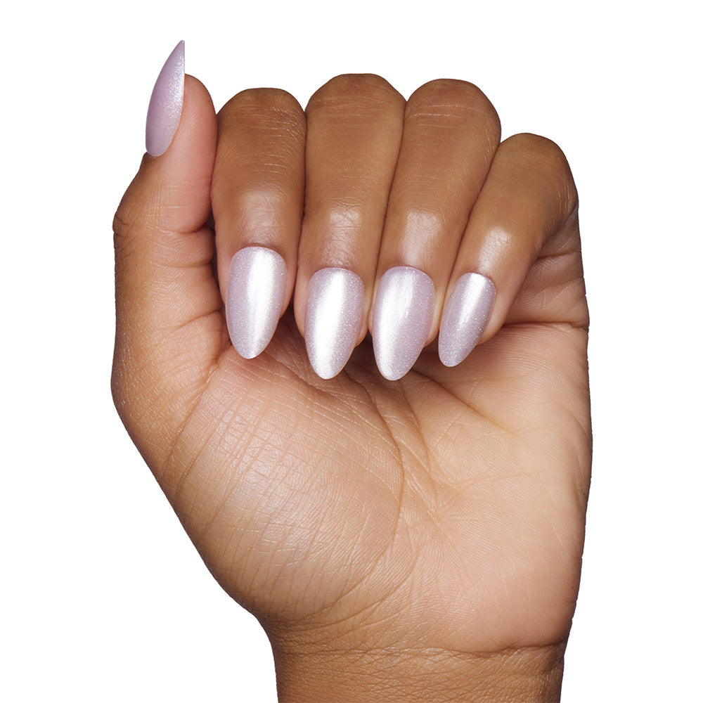 A hand with medium-brown skin displays short, almond-shaped nails painted with shimmery pale pink polish from the glamnetic Selenite set against a white background. - Product image