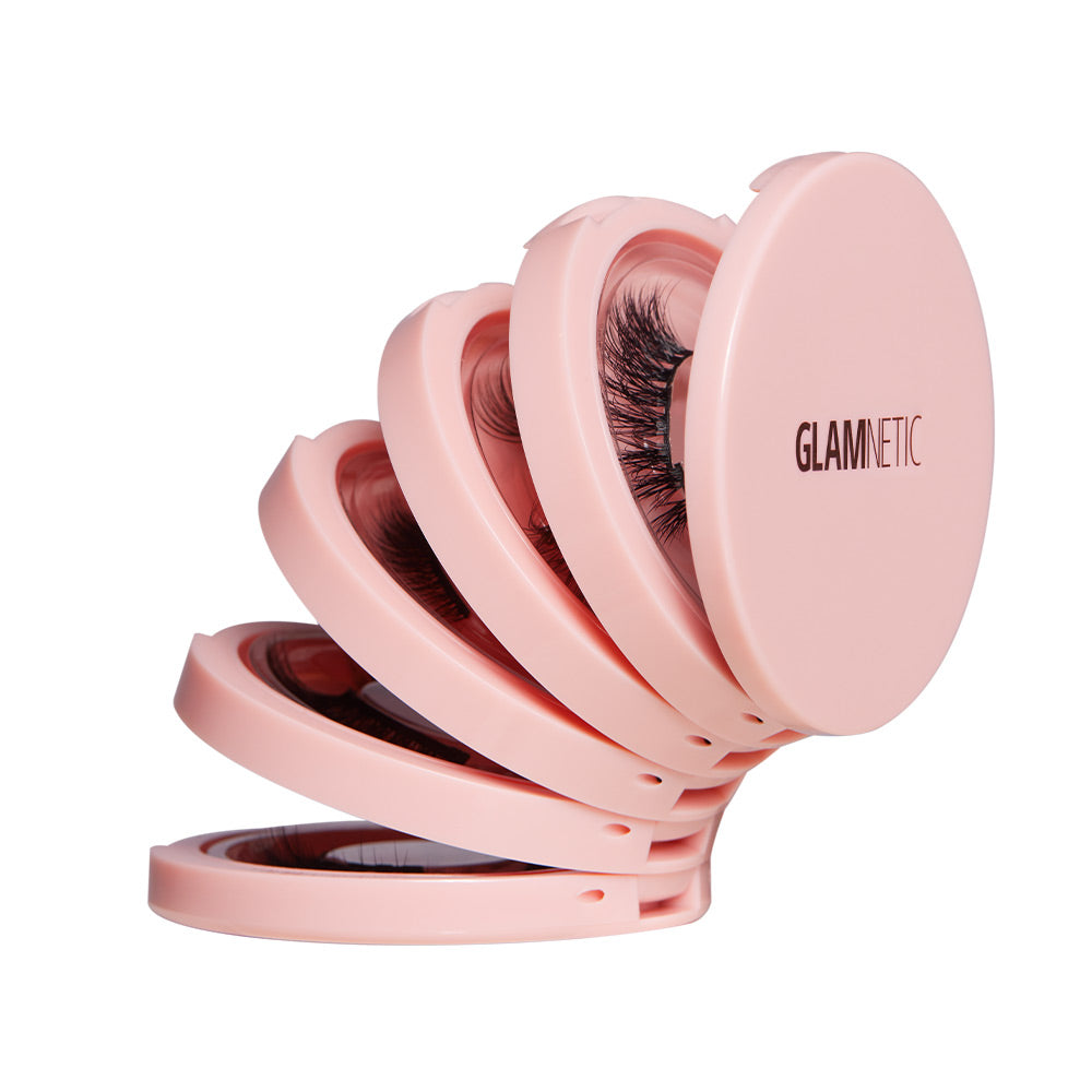 Four pink, round Glam & Go Travel Cases by glamnetic are fanned out, each holding a pair of magnetic lashes. The outer case features the glamnetic logo—ideal for storing your lash extensions on the go. - Product image