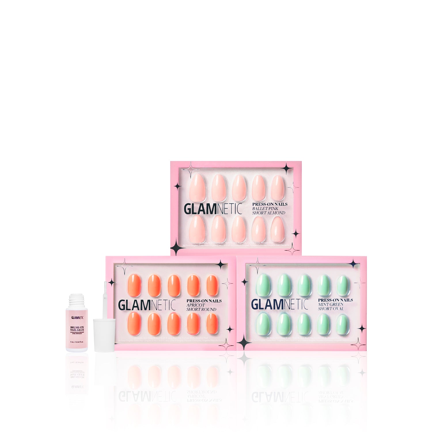 Three boxes of glamnetic Springtime Blooms press-on nails are stacked in pink, apricot, and mint green. An open nail glue bottle sits to the side, all against a white background. - Product image
