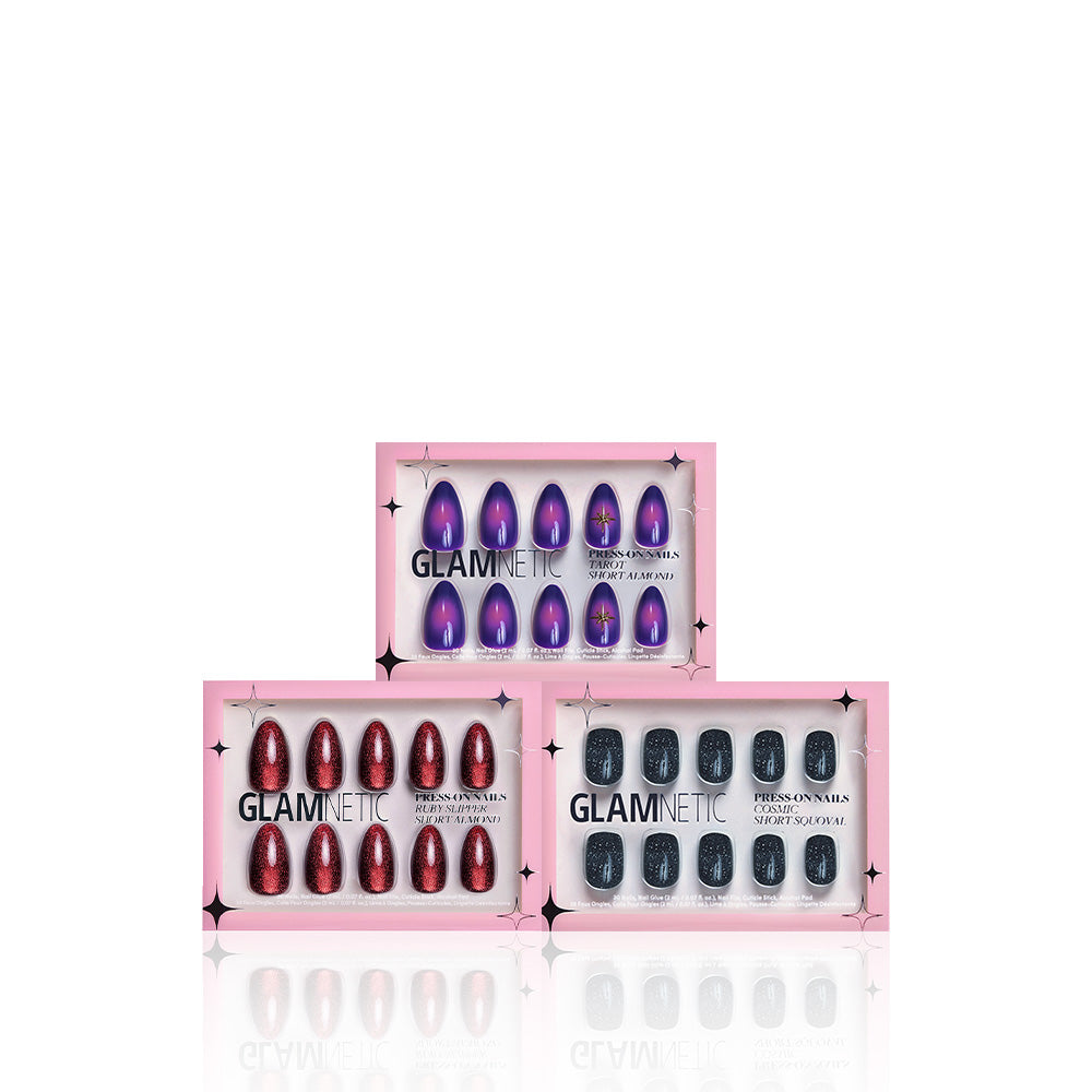 Three boxes of glamnetic press-on nails are displayed: the top shows purple Mystic Vision nails, the bottom left has red glitter Ruby Slipper nails, and the bottom right features black glitter nails. All three boxes have pink packaging. - Product image