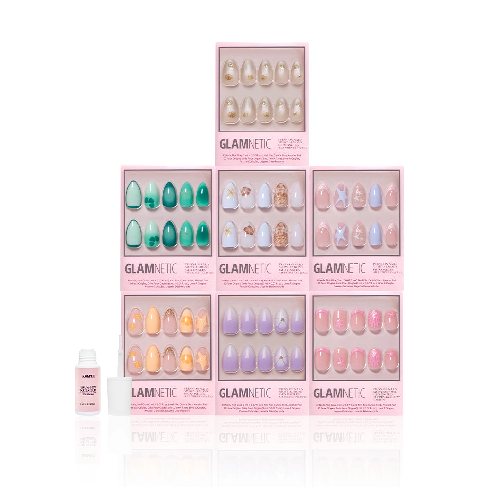 Seven boxes of glamnetic press-on nails, featuring the Mermaid Jewels set with ocean-inspired accents, are stacked in a pyramid. A nail glue bottle is placed to the left, all set against a white background. - Product image