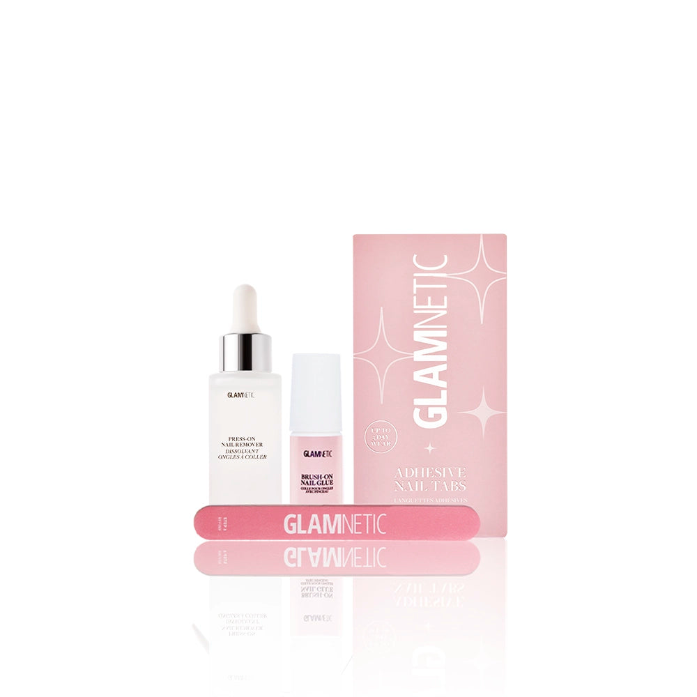 A set of glamnetic Press-On Essentials—featuring a dropper bottle, small cylindrical bottle, pink Adhesive Nail Tabs box, and two pink nail buffers with bold branding—displayed on a white background.