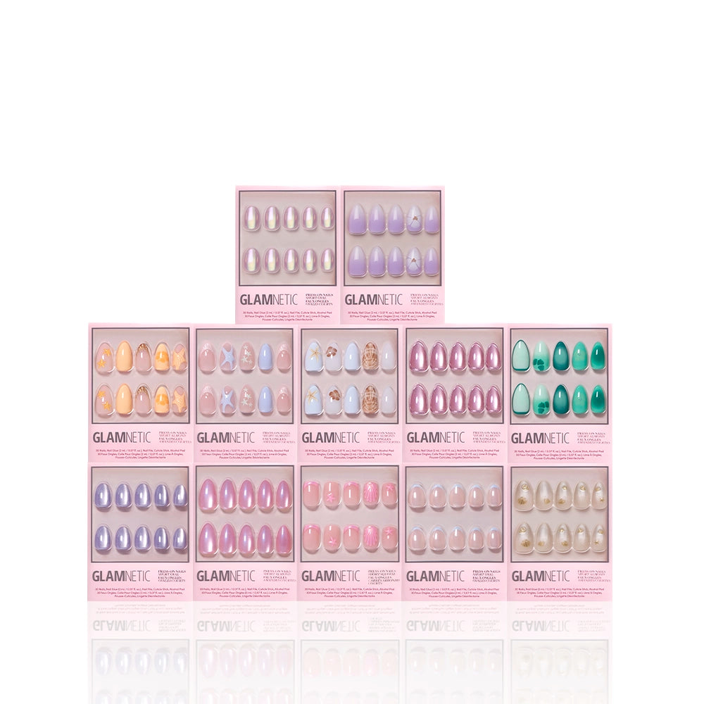 Ten boxes of glamnetic press-on nails from the Sirens Cove Collection are stacked pyramid-style against a white background, each box showcasing unique 3D nail art and designs through a transparent window. - Product image