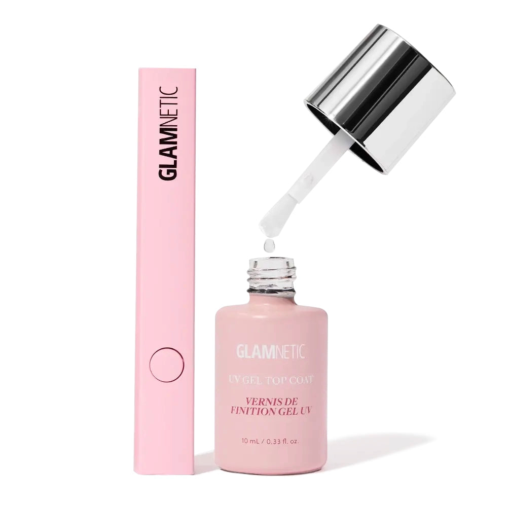 A bottle of glamnetic UV Gel Top Coat with brush applicator is held above its open bottle next to a pink glamnetic box and the Handheld LED UV Lamp—ideal for creating salon-quality manicures at home.