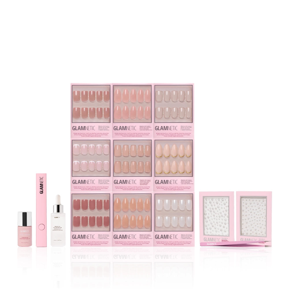 The glamnetic Timeless Studio Kit features pink-packaged Timeless Tones nail sets, a dropper bottle, nail glue, UV Gel Top Coat tube, and two Nail Decal Sticker packs—all arranged on a white background. - Product image