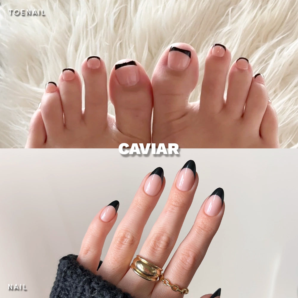Glamnetic Caviar Mani & Pedi bundle shown on hands and feet. Features glossy black French tips on natural pink base, with toenails displayed on a furry white rug and fingernails shown with gold rings on fingers. - Product image