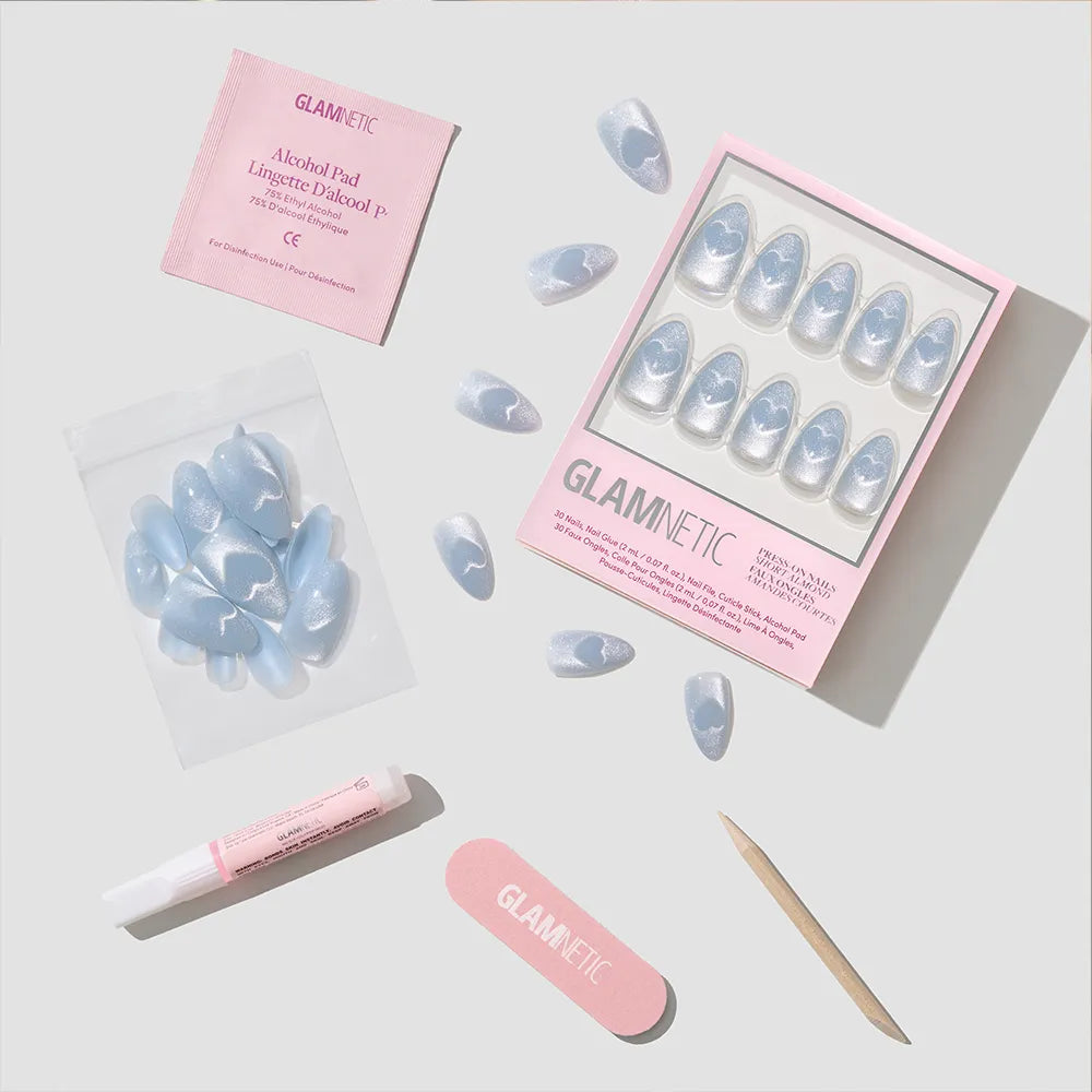 The glamnetic Cold Hearted set features short almond blue velvet press-on nails with white cloud designs, plus an alcohol pad, nail glue, nail file, and extra nails, all displayed on a light gray background. - Product image