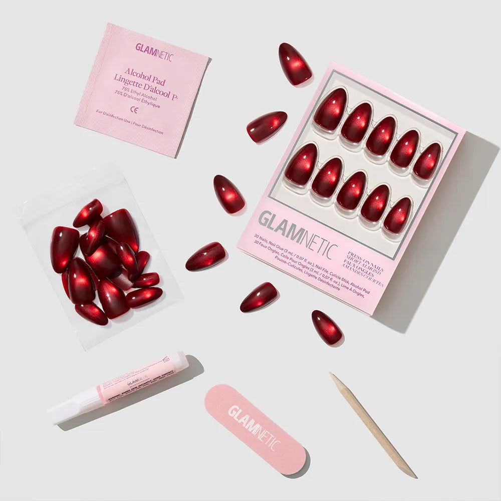 The glamnetic Frosted Cranberry set includes red short almond nails, a pink nail file, cuticle stick, glue tube, alcohol pad, and extra nails—perfectly arranged for a festive manicure. - Product image