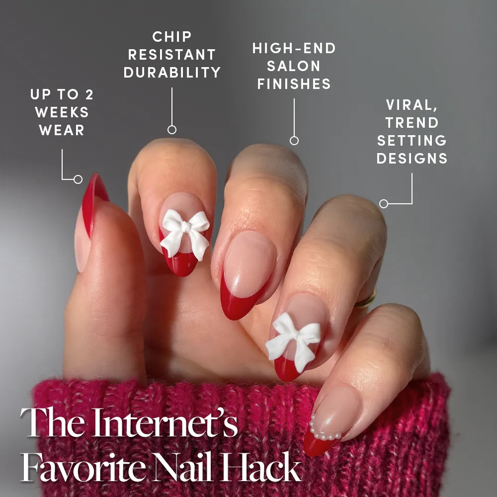 A hand with glamnetic's Ruby Ribbons red French tip almond nails, two adorned with 3D white bows, wears a pink sweater. Enjoy long wear, chip resistance, salon finish, and trendy designs—The Internet’s Favorite Nail Hack. - Product image