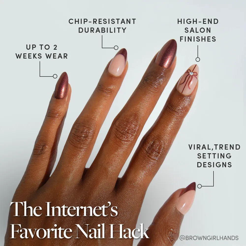 A hand with manicured short almond nails showcases glamnetic's "She's A Gift," featuring glossy maroon and nude shades with a delicate line accent. Enjoy salon-quality, chip-resistant wear for up to 2 weeks in a trend-setting design. - Product image