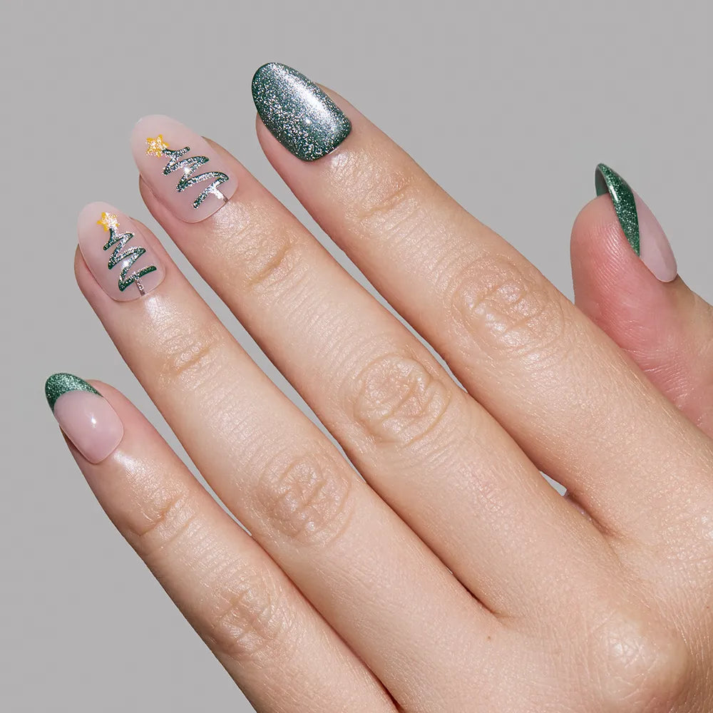 A manicured hand showcases glamnetic’s Velvet Pine on the thumb, pinky, and tips, while the middle and ring fingers feature Christmas tree nail art with gold stars—a festive holiday manicure set against a gray background. - Product image