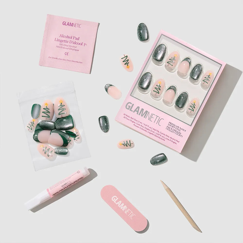 The Velvet Pine Christmas nail set by glamnetic features green, pink, and nude velvet pine nails with festive tree designs, plus an alcohol pad, nail glue, mini file, cuticle stick, and extra nails for a perfect holiday manicure. - Product image