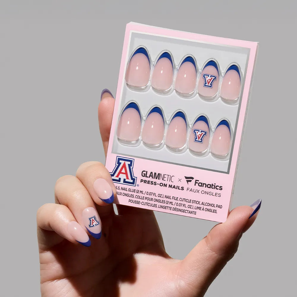 A hand displays the glamnetic Arizona Wildcats Press-On Nail Set featuring pink bases, navy French tips, and the team’s A logo—salon-quality nails in branded packaging, perfect for fans to show their Wildcats pride. - Product image