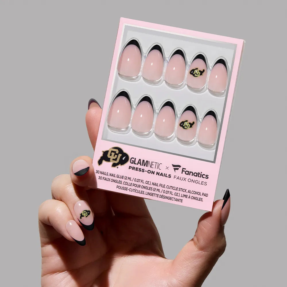 A hand holds a glamnetic Colorado Buffaloes Press-On Nail Set, showcasing salon-quality black French tip nails with the university logo on one. Matching nails are displayed on the person’s fingers. - Product image