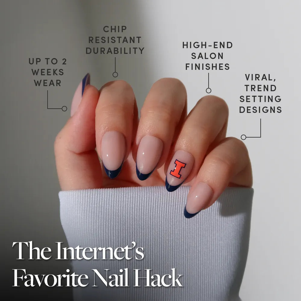 A hand wears glamnetic’s Illinois Fighting Illini Press-On Nail Set featuring long, blue French tips with an orange “I” accent—perfect for fans. Enjoy chip resistance, up to 2 weeks’ wear, high-end finishes, and trendy designs against a gray background. - Product image