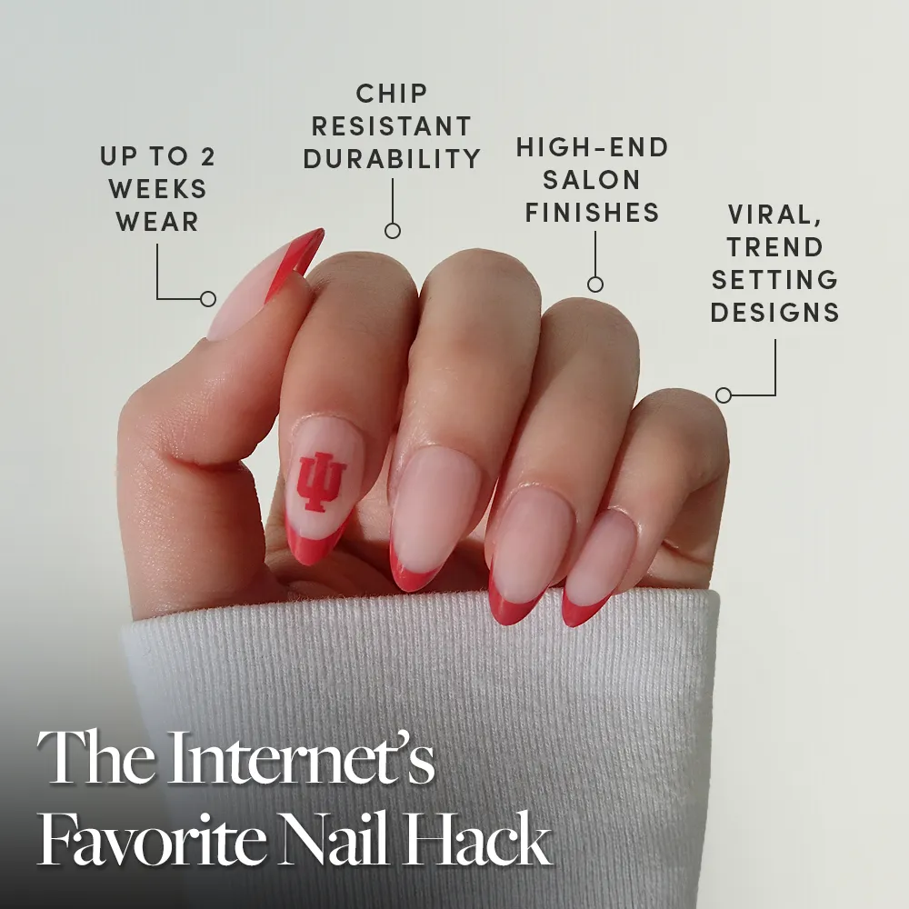 A hand with long, almond-shaped nails features the glamnetic Indiana Hoosiers Press-On Nail Set—pink base, crimson French tips, and Hoosiers logo. Enjoy up to 2 weeks of chip-resistant, salon-quality wear with trend-setting designs that are going viral. - Product image