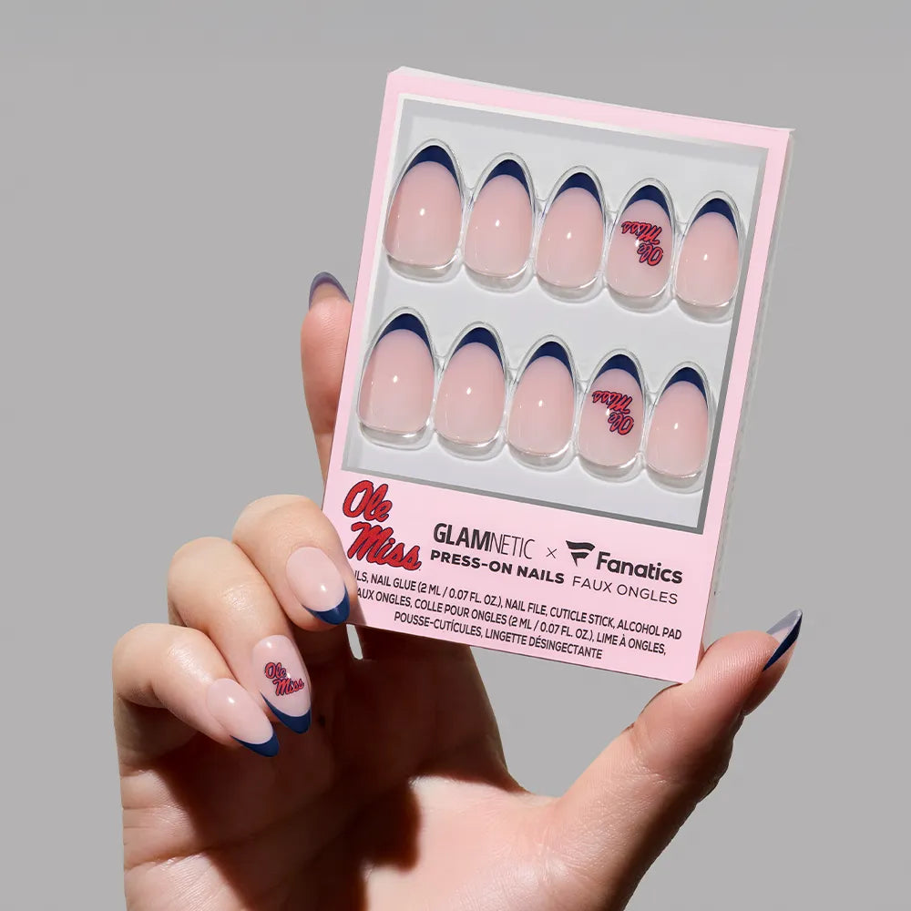 A hand holds the glamnetic Mississippi Rebels Press-On Nail Set with a pink base, dark blue French tips, and red “Ole Miss” accents—perfect salon-quality nails to show your team spirit. - Product image