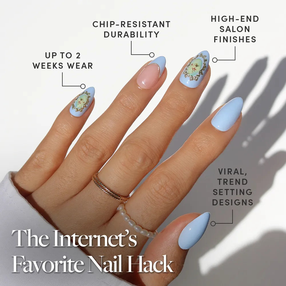 A hand with long, almond-shaped nails in glamnetic's Angel in Blue—pastel blue and nude with 3D gold accents. Enjoy chip-resistant durability, high-end finishes, viral designs, and up to two weeks of wear. - Product image
