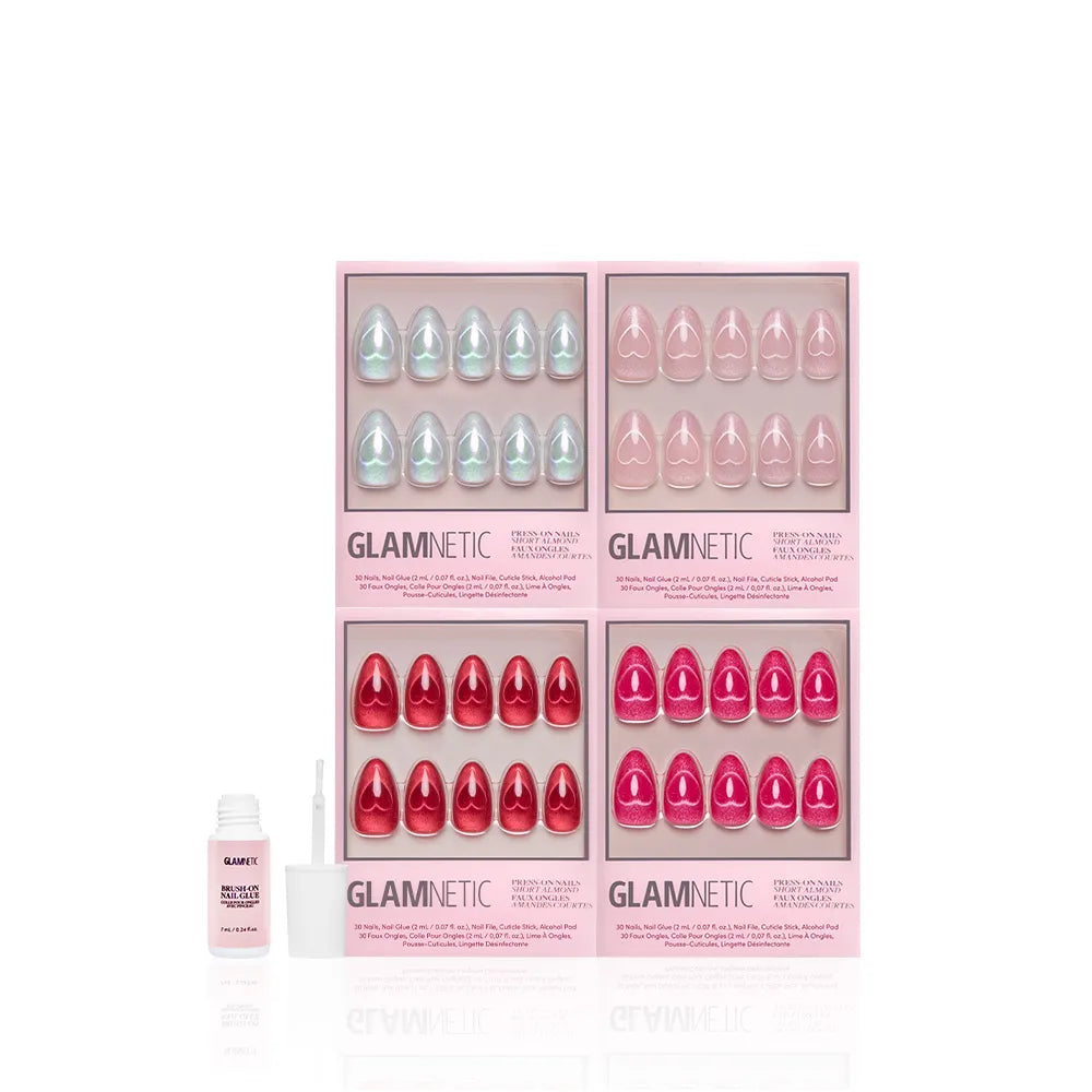 Four boxes of glamnetic Cupid's Magnetic Hearts press-on nails in pastel blue, coral, pink, and red are arranged in two rows. To the left is a small bottle of glamnetic nail glue with applicator. All set against a white background. - Product image