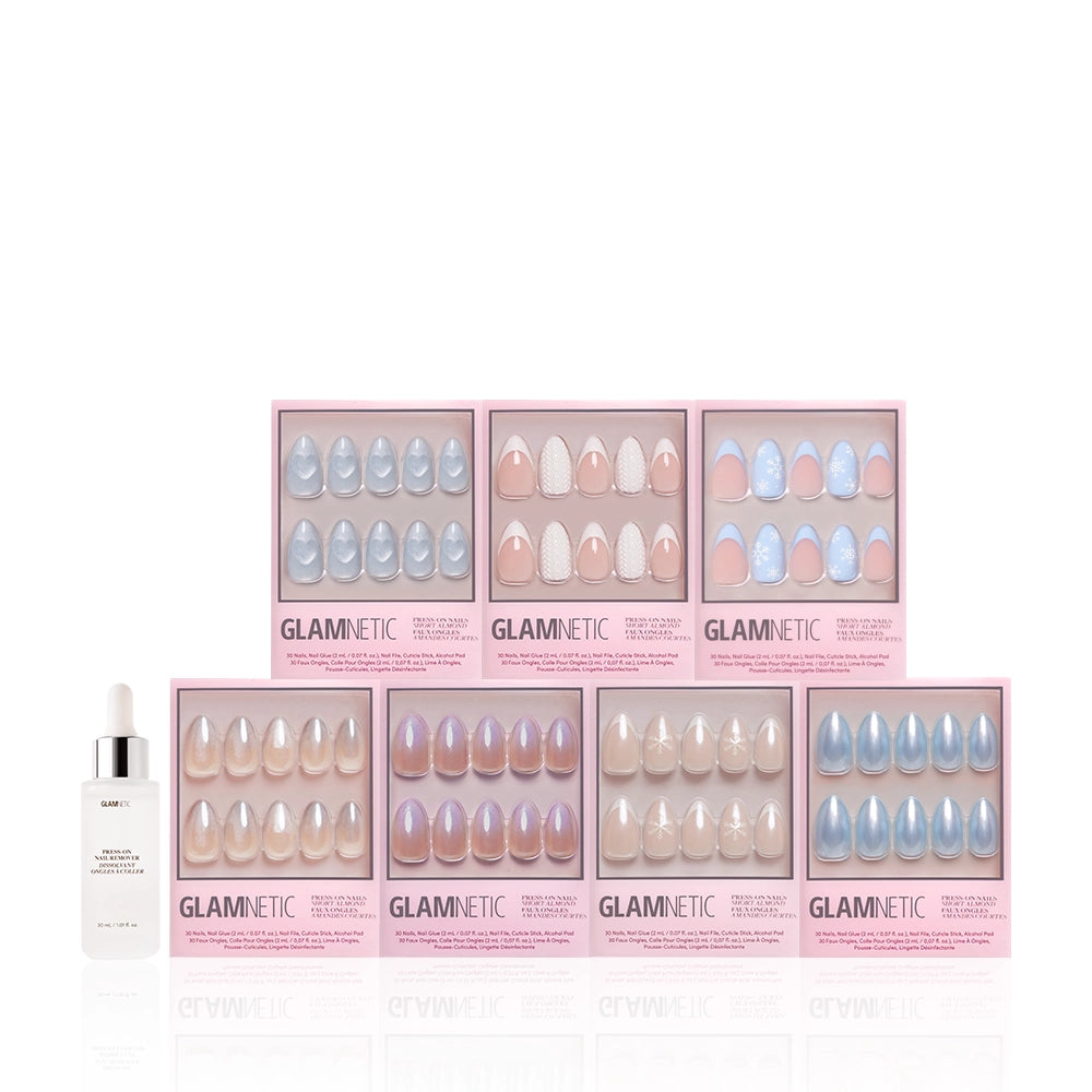 Seven boxes of Glamnetic's Frozen Over press-on nails, featuring pastel and winter designs like snowflakes, are arranged in two rows with a nail remover or cuticle oil bottle on the left. The background is white. - Product image