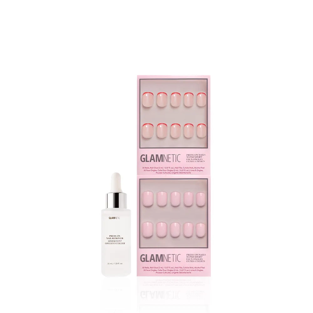 A super short Glamnetic Super Short & Sweet press-on nail set in light pink shades with red-accented French tips, displayed in two pink boxes beside a white Glamnetic Nail Adhesive bottle. - Product image