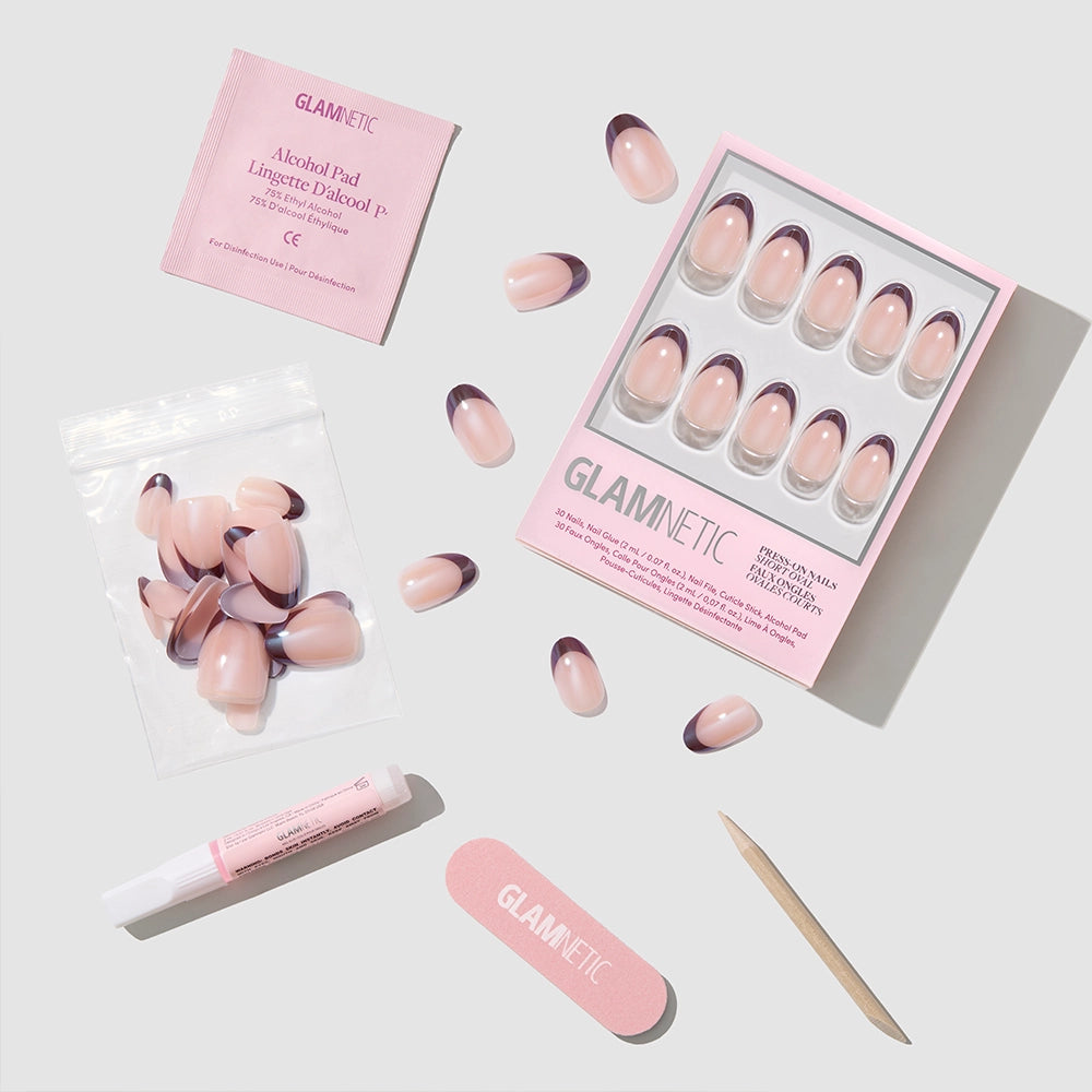 The Glamnetic Cherry Mood short oval press-on nails set features pink and purple tips, a nail file, wooden cuticle stick, nail glue, alcohol pad, and extra nails—all displayed neatly on a white background. - Product image