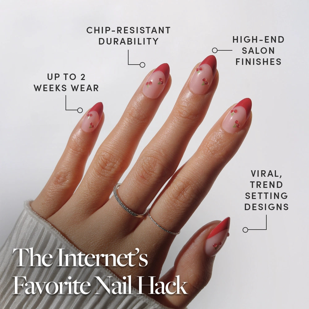 A hand displays glamnetic Cherry Bomb press-on nails—almond shape with pink bases, bold red tips, and gold accents. Enjoy chip-resistant durability, up to 2 weeks wear, and high-end trendy finishes. - Product image