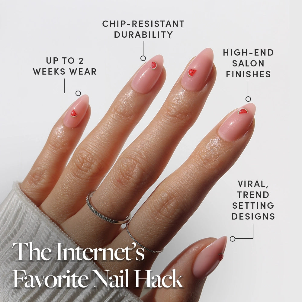 A hand with long, almond nails flaunts glamnetic’s Juicy Slice press-ons in pink with tiny red hearts. Text highlights “chip-resistant durability,” “up to 2 weeks wear,” “high-end salon finishes,” and “viral, trend-setting designs.”. - Product image