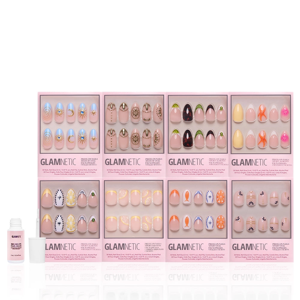Eight sets of glamnetic 3D Souvenirs nail sets in colorful designs are displayed in pink boxes with a small white bottle of glamnetic Nail Glue on the left, perfect for salon-quality nails at home, all shown against a white background. - Product image