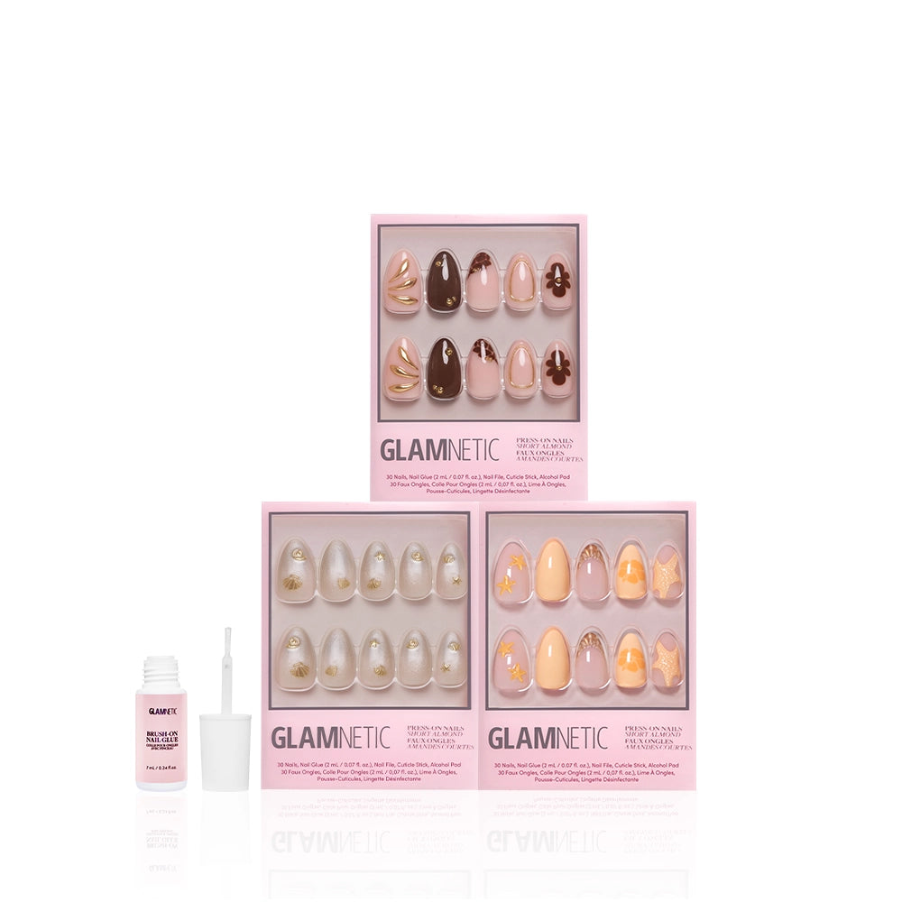 Three boxes of glamnetic Sun & Sand press-on nails with pink packaging, each showing ten gold, nude, and peach tropical short almond manis. Nail glue bottle and brush are beside the sets on a white background. - Product image