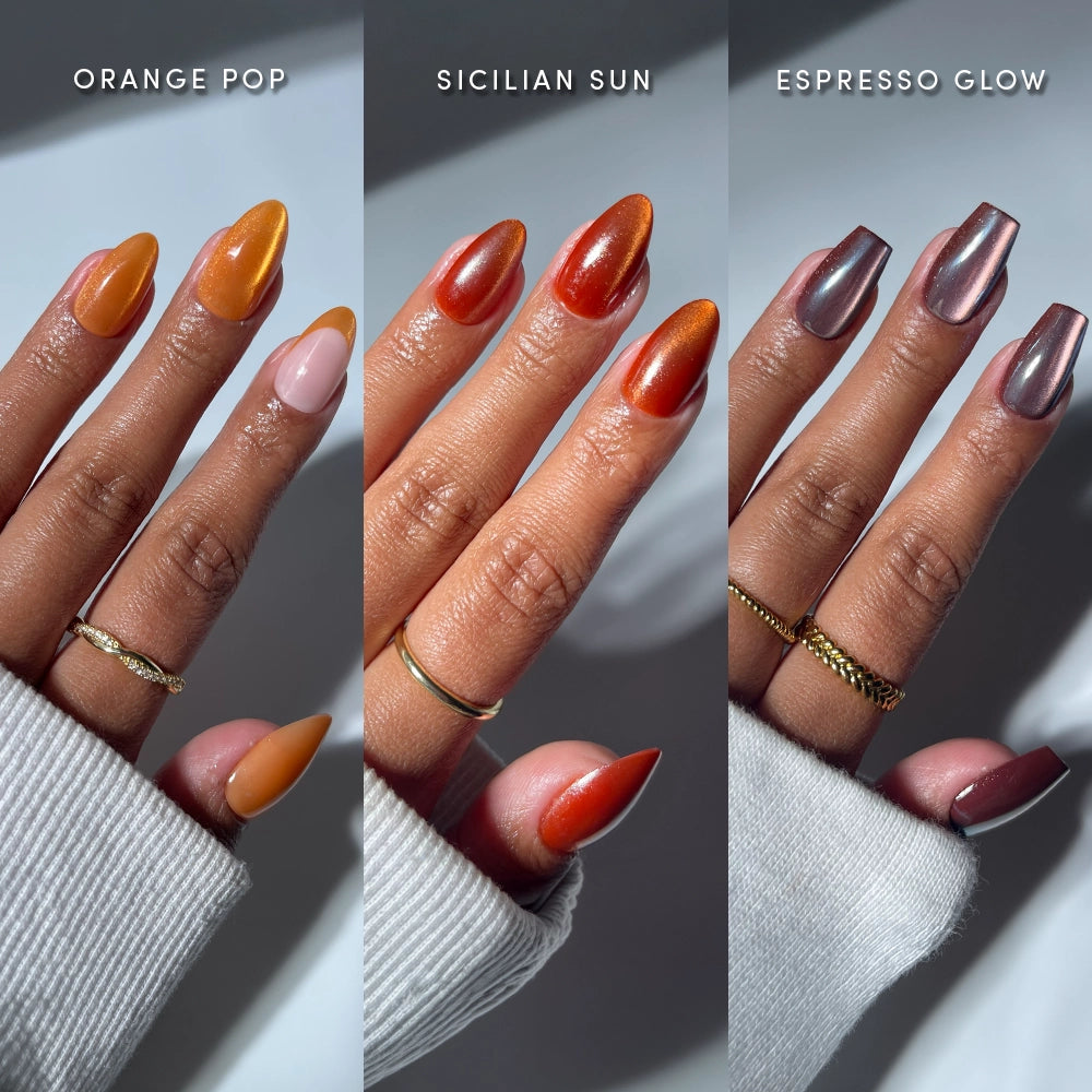 Three hands showcase almond nail sets: the orange shade "Orange Pop," shimmering amber "Sicilian Sun," and metallic brown "Espresso Glow" from glamnetic's La Vida Velvet collection. Each hand is adorned with gold rings.