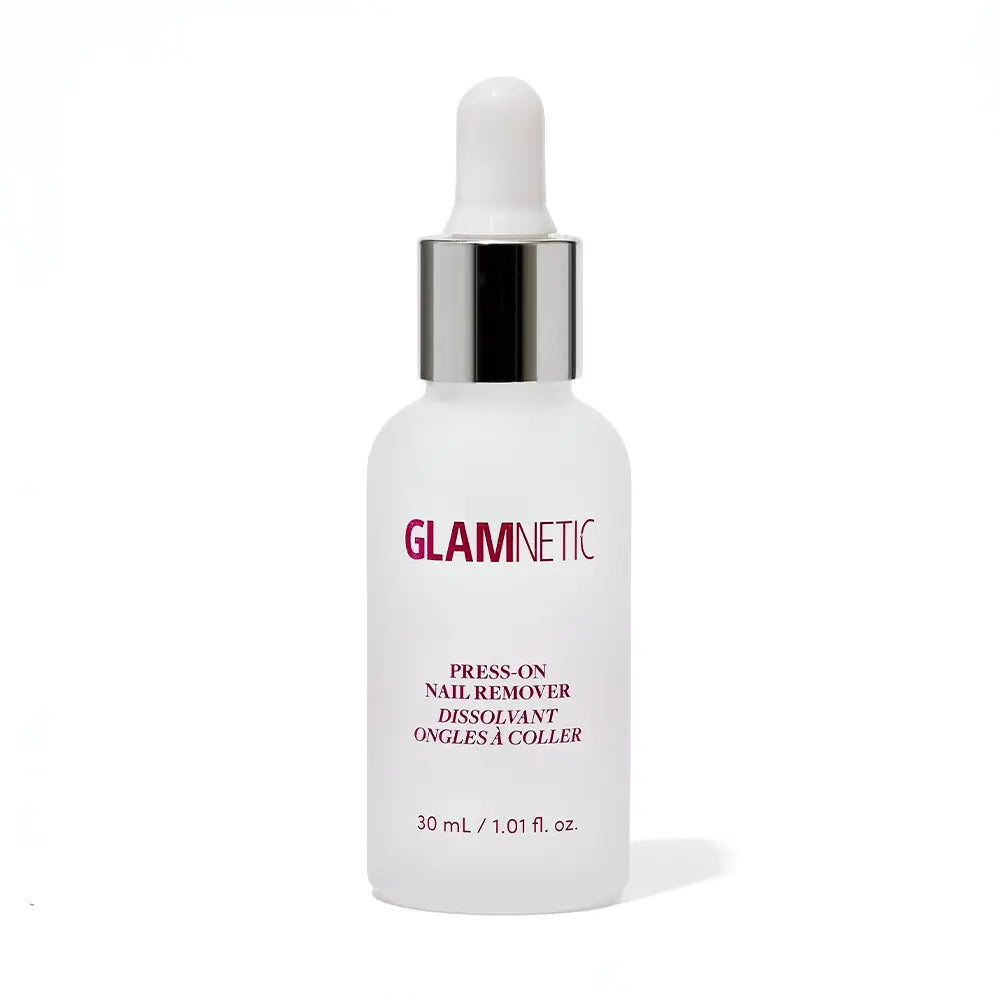 A white dropper bottle labeled glamnetic Press-On Nail Remover with pink and silver text sits on a white background. The acetone-free formula is gentle on natural nails, with a circle nearby stating Packaging May Vary.
