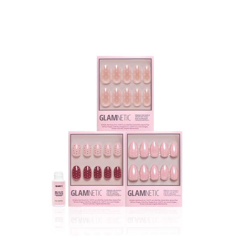 Three glamnetic Polka Pop press-on almond nail sets, each with unique pink and polka dot designs, are displayed in their packaging. A small white bottle of nail glue sits to the left on a white background. - Product image