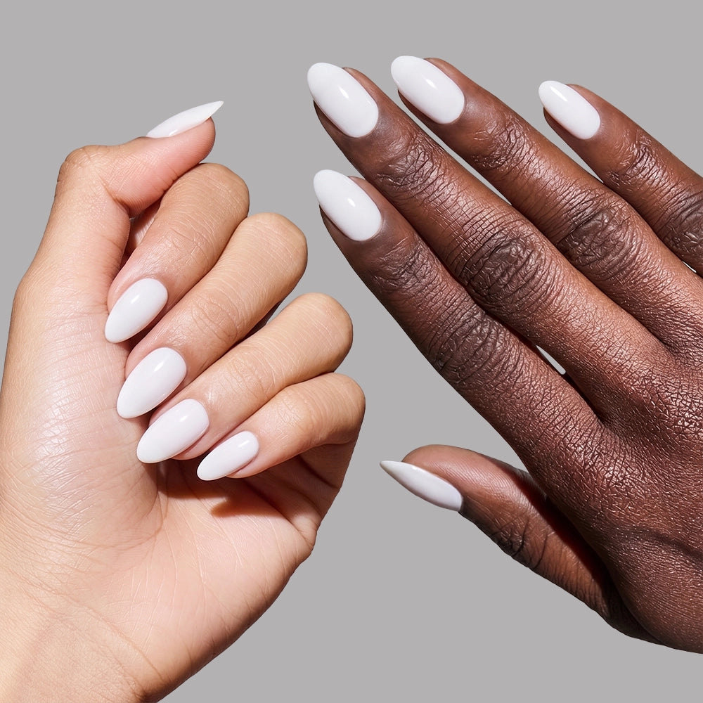Two hands—one light, one dark—showcase glossy white "Angel" press-on nails from glamnetic with a short almond shape, set against a plain gray background. - Product image