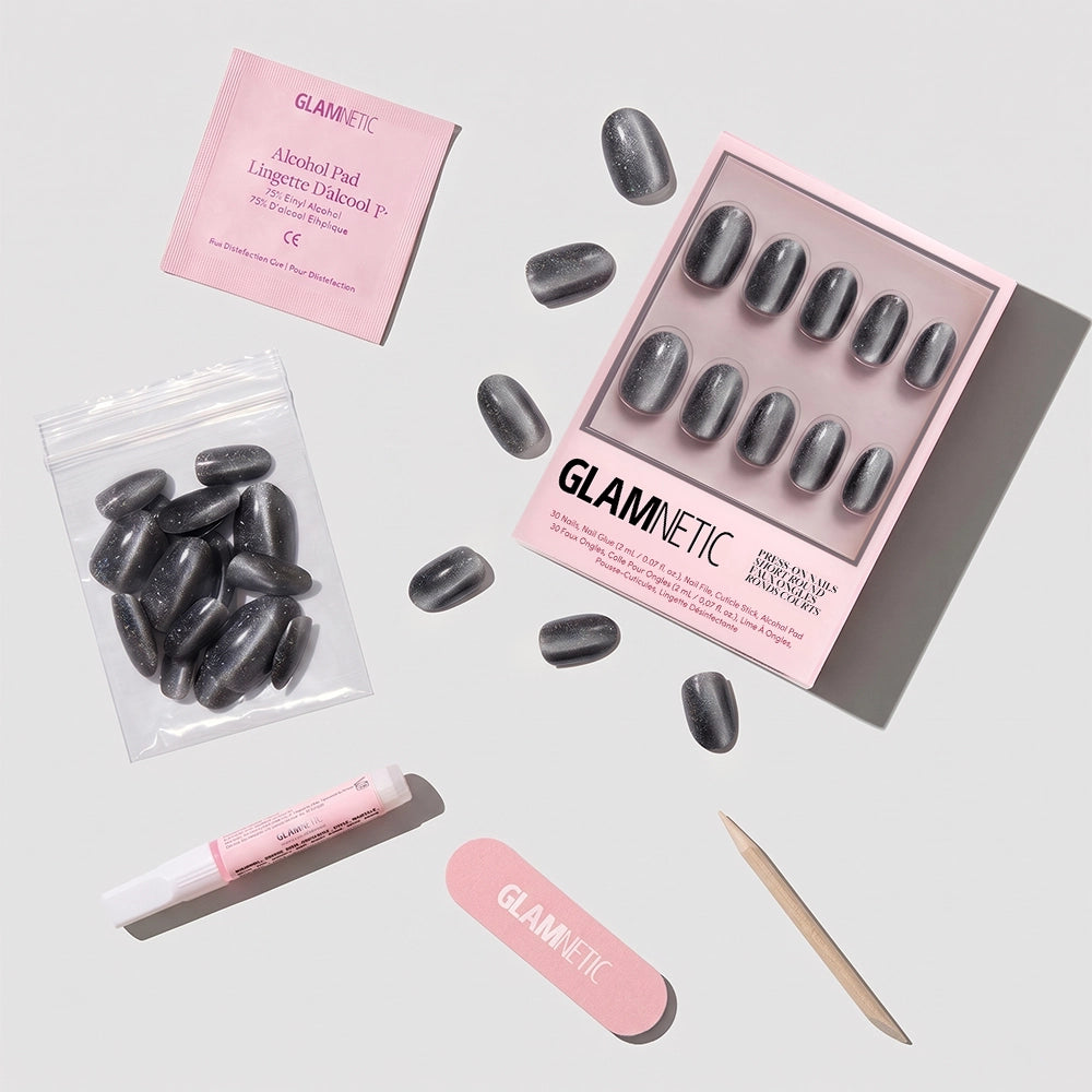 The "Galactic" glazed press-on nails set by glamnetic features a gray marble design and comes with an alcohol pad, nail glue, nail file, wooden cuticle stick, and extra nails—all displayed neatly on a white background. - Product image