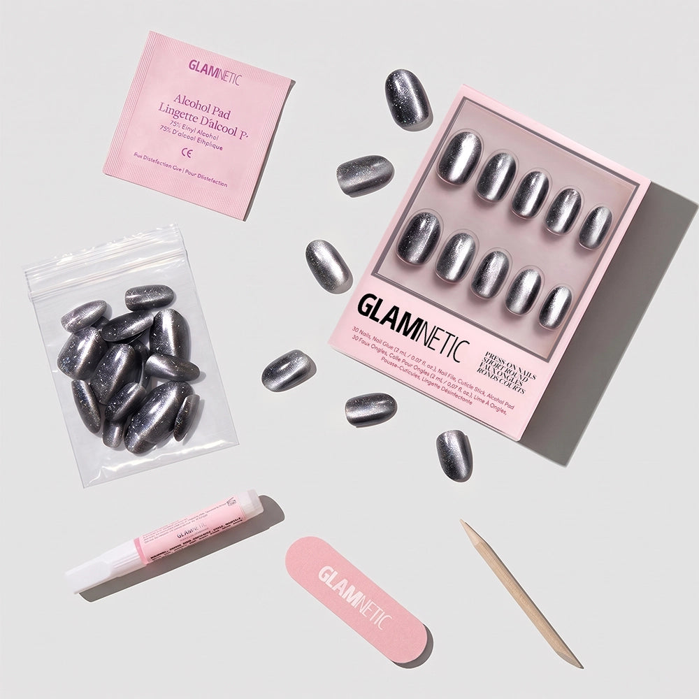 A set of glamnetic Galactic press-on nails in metallic silver short round style is displayed with an alcohol pad, nail glue, nail file, cuticle stick, and extra nails—all in signature pink packaging. - Product image