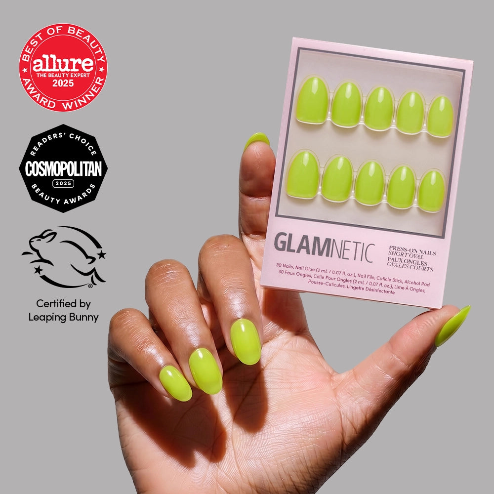 A hand with bright lime green, short oval glamnetic “Lime Green” press-on nails holds the matching vegan, cruelty-free package. Allure, Cosmopolitan awards and Leaping Bunny certification badges appear on the left against a gray background. - Product image