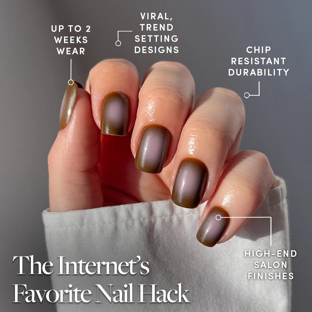 A hand with short squoval nails wears glamnetic's Eclipse taupe brown ombré press-ons near sunlight. Up to 2 weeks wear, viral designs, chip resistance, and high-end finishes. The Internet’s Favorite Nail Hack is written below. - Product image