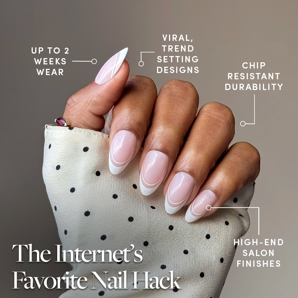 A hand with classic French tip nails holds a white and black polka dot cloth. glamnetic Paris press-ons offer up to 2 weeks wear, chip-resistant durability, salon-quality finish, and viral trend-setting designs for modern style. - Product image