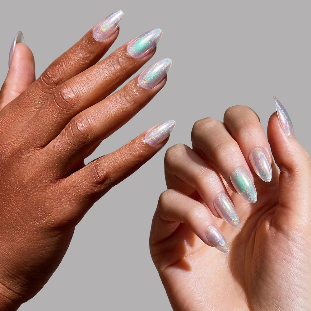 Two hands—one light, one dark—display long, almond nails painted with glamnetic’s Stardust holographic polish against a plain gray background. - Product image