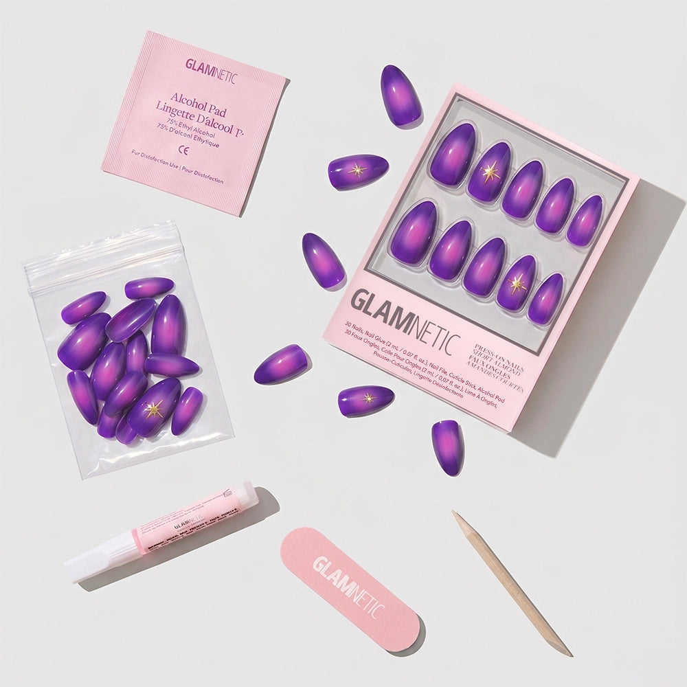 Glamnetic’s Tarot set includes short purple almond press-on nails with gold stars, a pink nail file, wooden cuticle stick, nail glue, alcohol pad, and extra nails—all displayed on a white background. - Product image