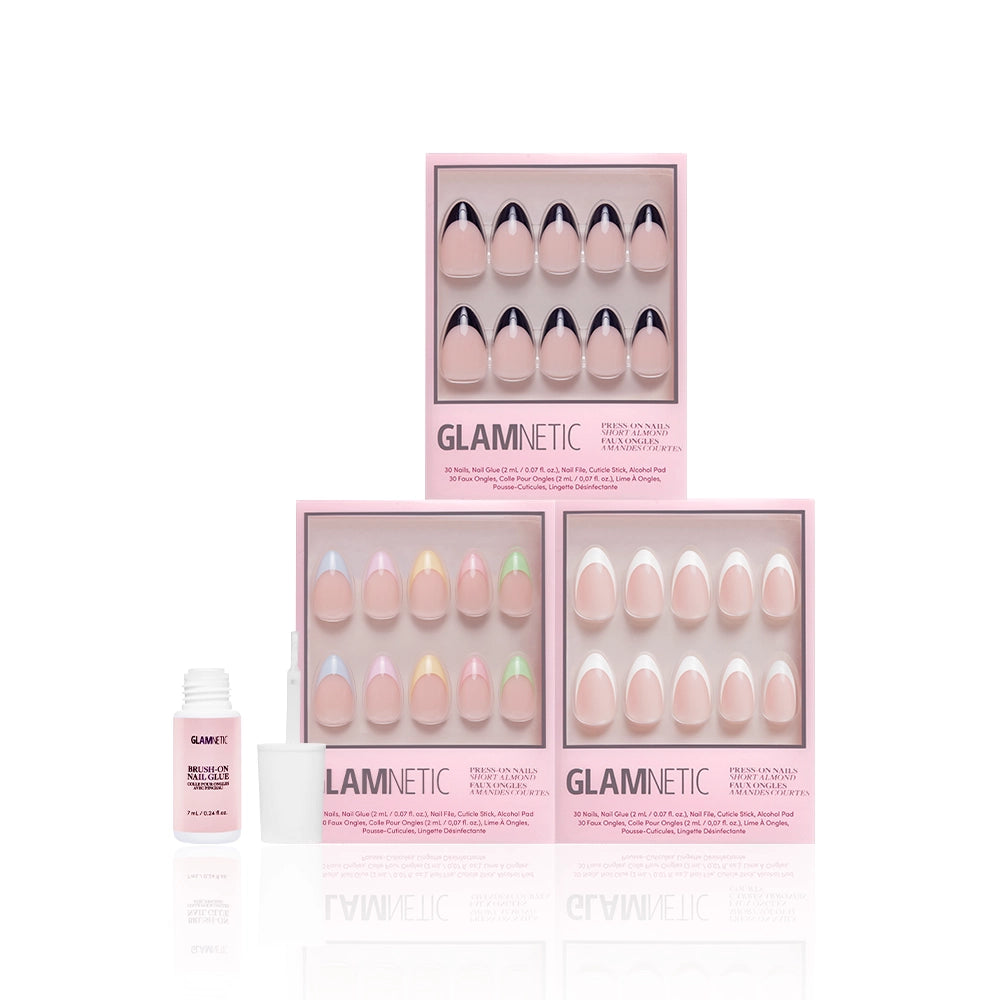 Three boxes of the glamnetic Frenchie Bundle are stacked, showcasing a variety of nail designs such as a chic short almond set and elegant French tip nails in pink packaging. To the left of the boxes is a small bottle of glamnetic nail glue with an applicator. - Product image