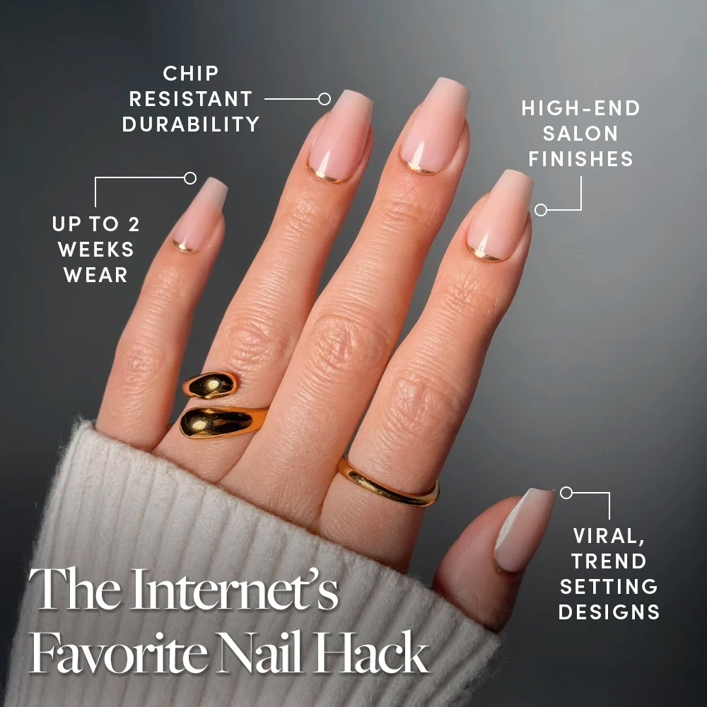 A hand displays glamnetic's Gold Goals: long, nude, square press-on nails with gold accents and foil. Enjoy chip resistance, high-end finishes, trendy designs, and up to 2 weeks of wear. Rings and a sweater sleeve complete the chic look. - Product image