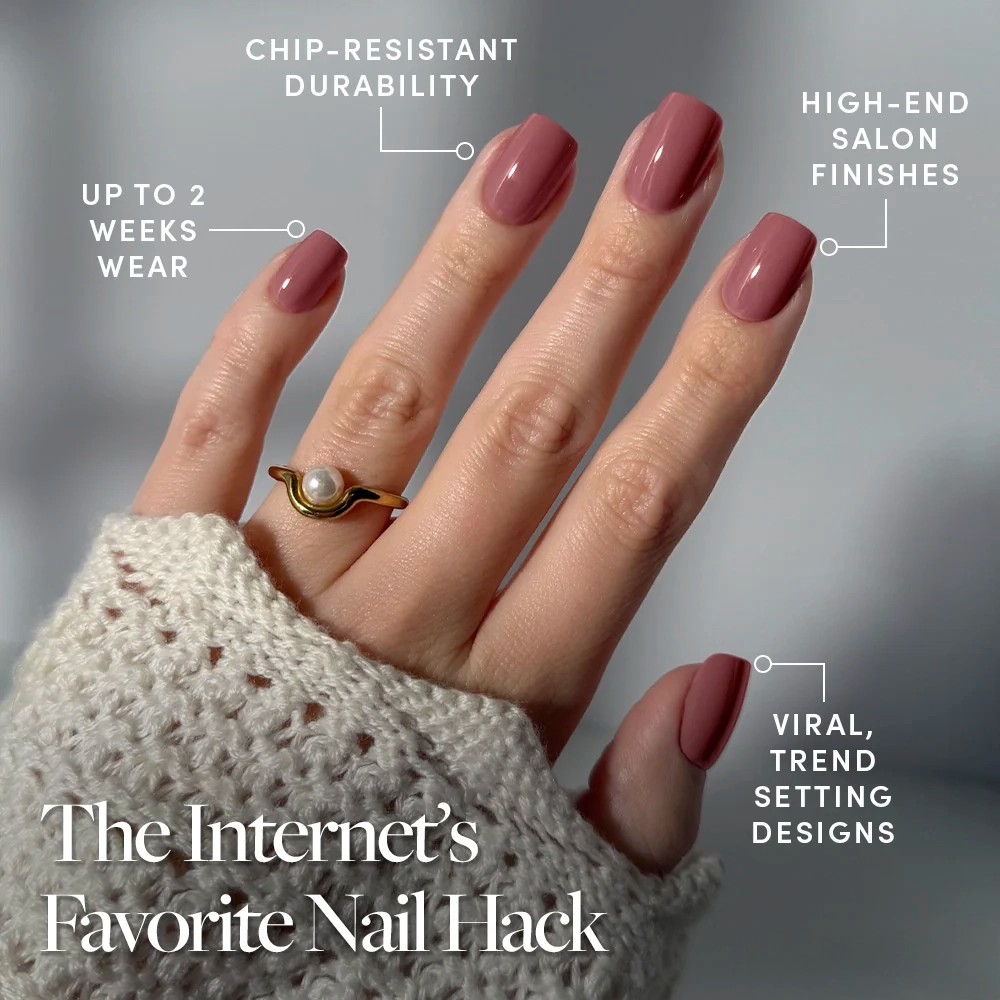 A hand wears glamnetic's Mauve On glossy mauve press-on nails in a short squoval shape, featuring chip-resistant durability, salon-quality finish, up to 2 weeks wear, and viral trend designs. Shown with a pearl ring and textured sweater. - Product image