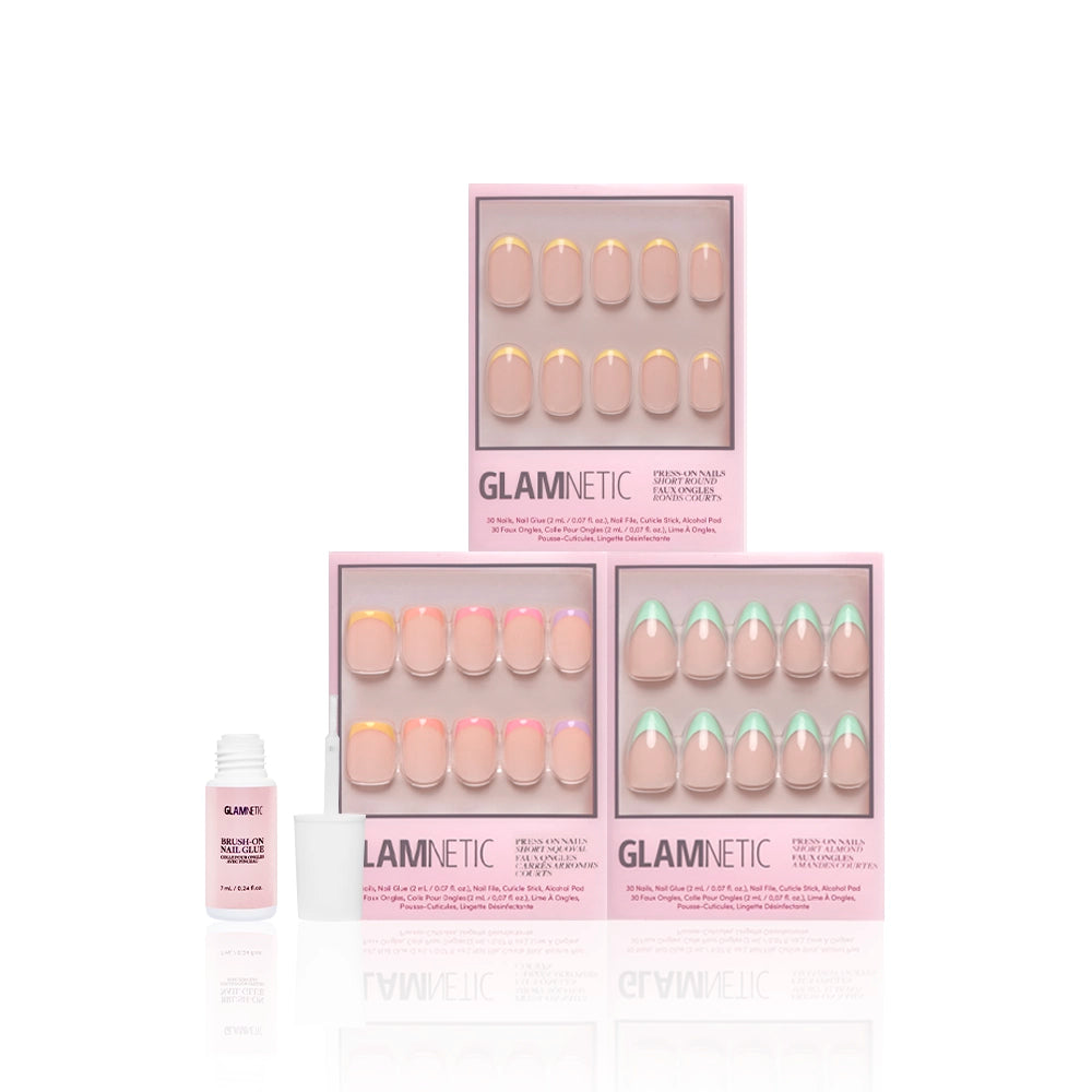 Three sets of glamnetic À La Ann press-on nails in pink boxes, each with colorful French tips, are stacked together. In front on the left, an open bottle of nail glue is ready for salon-quality durability at home. - Product image